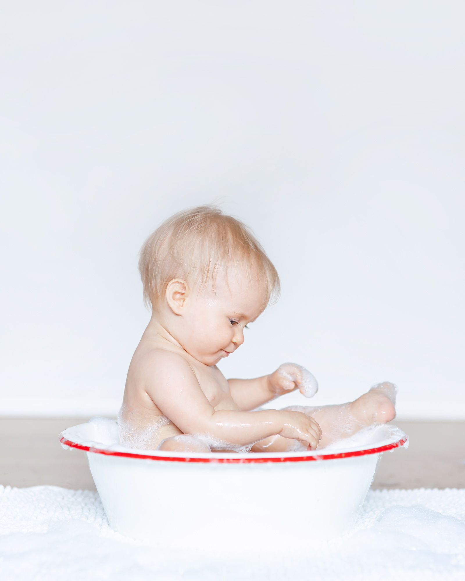 Infant playing with bubbles in a bath tub photo session